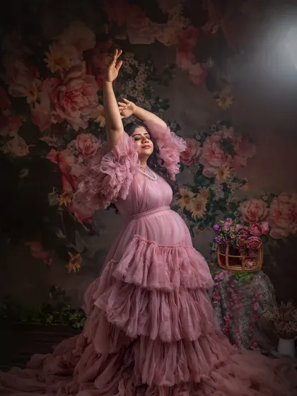 A joyful and expressive pose against a vibrant floral backdrop. The movement in the arms and the flowing gown create a sense of celebration and life.