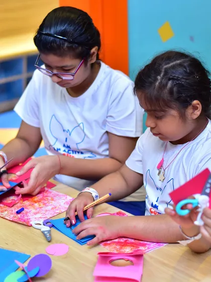Two girls concentrate on a detailed craft project during a workshop. I provide all the materials needed for kids to dive into creative activities and express their artistic talents.