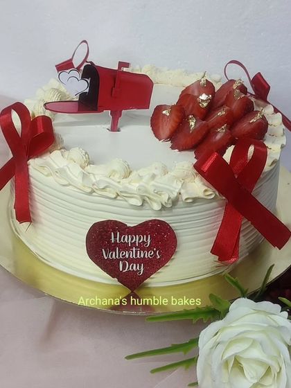 A sweet Valentine's Day cake with a mailbox, fresh strawberries, and red ribbons.