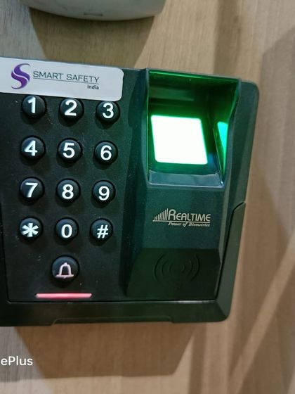 A close-up of the Realtime TD1D reader. The green light on the sensor shows it is ready to scan a fingerprint for access.