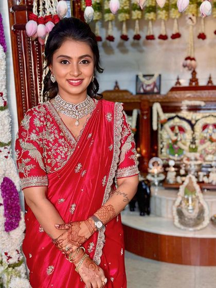 A smiling portrait in front of the family's traditional pooja setup.