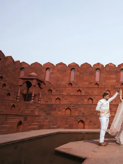 A dynamic shot of the couple dancing at the base of a historic step-well, with the expansive red walls creating a breathtaking backdrop for their pre-wedding photo.