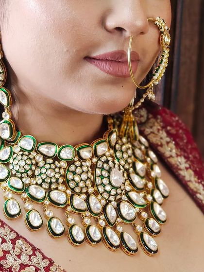 A close-up of a magnificent Pachi Kundan necklace with large uncut stones and green enamel work. The details on this piece are exquisite.