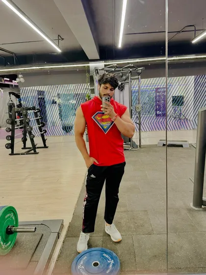 A relaxed full-body pose in the gym.