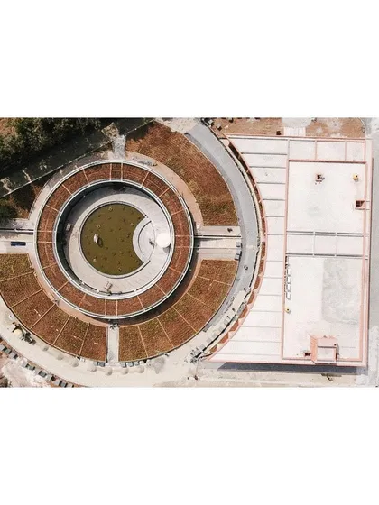 A bird's-eye drone shot of the memorial during its final stages, showing the circular form and the surrounding landscape taking shape.