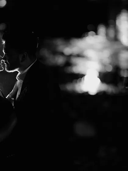 A beautiful black and white silhouette of a couple about to kiss, with the moonlight reflecting on the water behind them. This is a classic and artistic romantic shot.