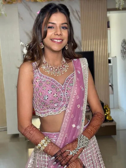 This shot shows the full look, with the hairstyle complementing her pink lehenga. The small floral accents in her hair tie the whole look together.