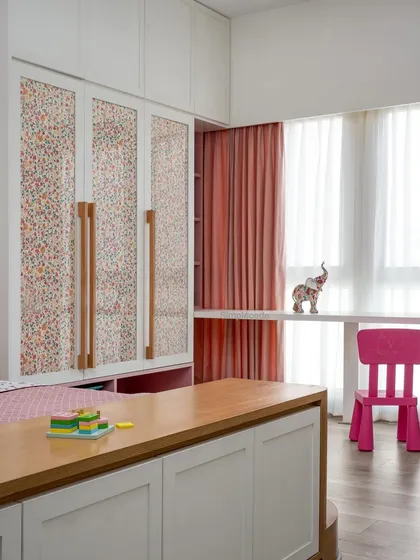 The daughter's bedroom in the 'Cover me in Sunshine' project features these charming wardrobe shutters with fabric sandwiched between glass panels, complemented by custom wooden handles.