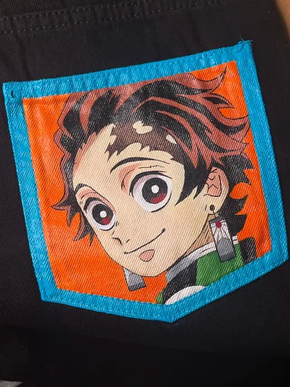 A hand-painted portrait of Tanjiro from 'Demon Slayer' on the pocket of a pair of black jeans.