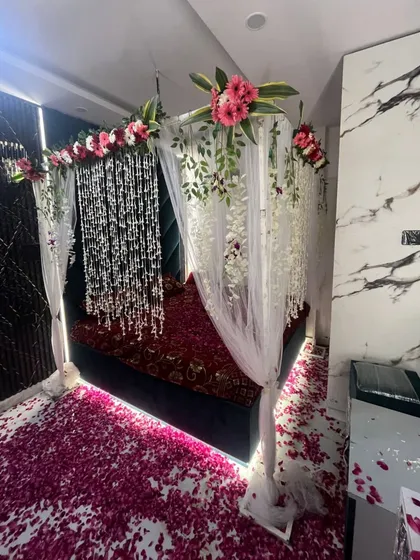 The wedding night room decoration from another angle, showing the sheer drapes and floral arrangements that frame the bed.