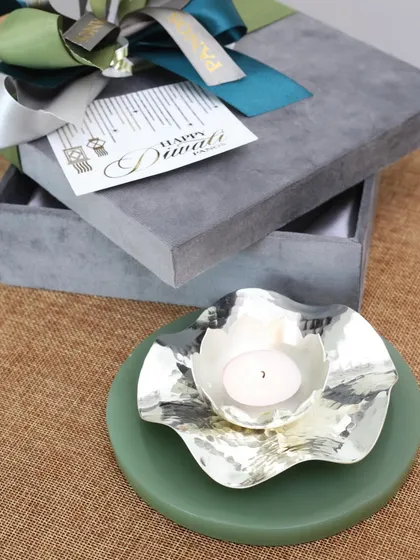 This silver-plated diya features a hammered, abstract flower shape on a serene green onyx base. It’s a contemporary design that adds a touch of grace to your sacred space.