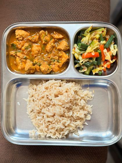 A simple and healthy meal of brown rice with chicken curry and sautéed mixed vegetables.