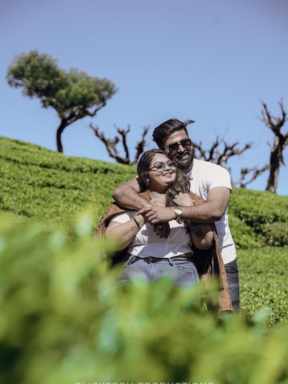 A happy couple embraces in a sunny tea plantation in Ooty, showcasing a beautiful destination shoot filled with natural light and greenery.