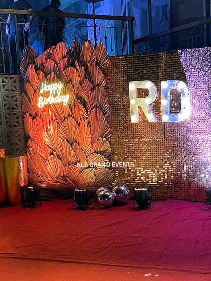 A clear, front-facing shot of the outdoor birthday setup, highlighting the contrast between the shimmering gold and the bold orange decor.