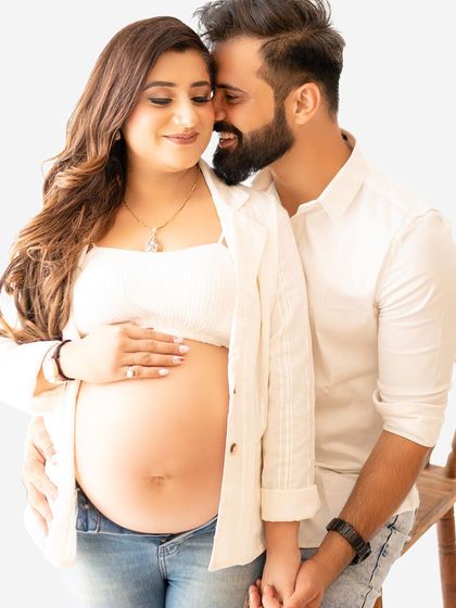 A casual and intimate maternity portrait. Sometimes the simplest outfits, like a white top and jeans, allow the focus to be entirely on the beautiful baby bump and the couple's connection.