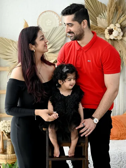 A loving family portrait with a natural, bohemian feel. The parents look on adoringly as their little girl sits happily between them.