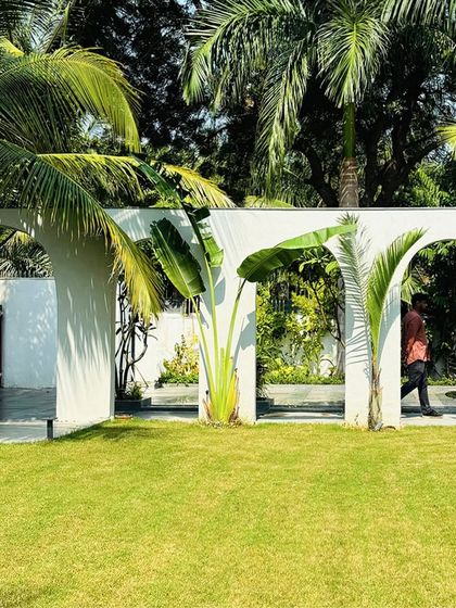 The arched wall acts as a permeable screen, separating the driveway from the central lawn while allowing glimpses through. The planting is strategically placed to enhance this sense of layering and discovery.