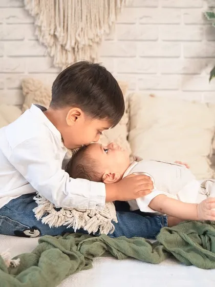 A protective big brother giving his baby brother a gentle kiss on the forehead. These are the moments that melt my heart.