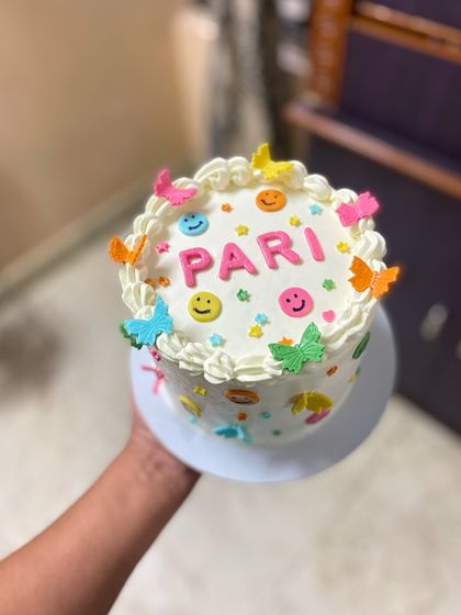 A hand-held shot of the smiley and butterfly cake, showing the details all around.