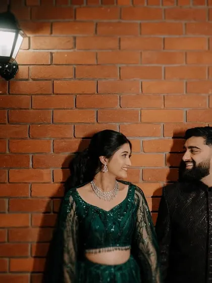 Rahul and Anjali share a look against an exposed brick wall. This kind of urban, rustic backdrop can create a modern yet intimate feel for couple portraits.