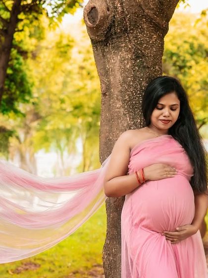 The golden hour light adds a magical glow to this outdoor maternity photo. The gentle breeze catching the pink fabric creates a truly breathtaking effect.