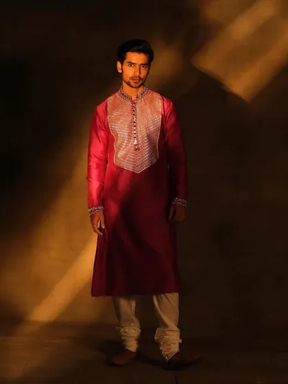 A groom in a deep magenta kurta. The makeup is minimal, focusing on creating a healthy complexion that looks great on camera, proving that a little grooming goes a long way.