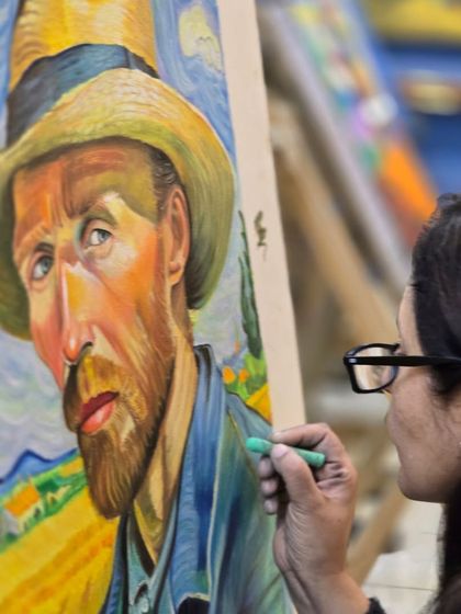 An artist at her easel, carefully adding green pastel to her Van Gogh-inspired portrait, demonstrating her focus and technique.