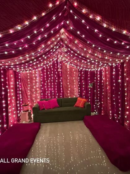A wide shot of the cozy living room tent setup. The magenta fabric canopy and floor seating create an intimate and festive atmosphere for guests to relax and celebrate.