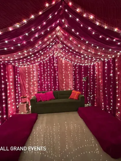 A wider view of the tented seating area we created inside a home. The magenta drapes and fairy lights on the ceiling and walls create a rich, immersive experience for guests.