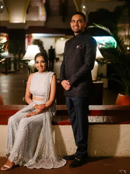 A classic, full-length portrait of the couple at their Sangeet, showcasing their coordinated and elegant evening attire.