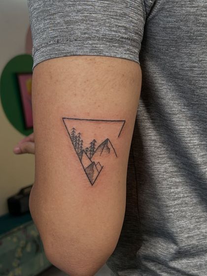 A minimalist mountain range and forest scene contained within a triangle. This clean, geometric design is perfect for anyone who loves nature and adventure.