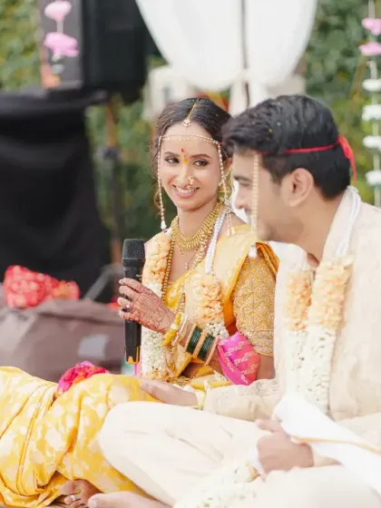 The bride speaks during the ceremony, sharing a smile with her groom. This candid moment captures the personal touches and shared joy within the traditional Marathi wedding rituals.