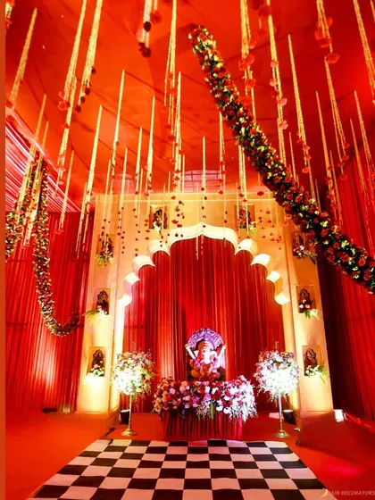 A beautiful setup for a prayer or puja ceremony, with a Ganesha idol at the center of a red and gold themed space.