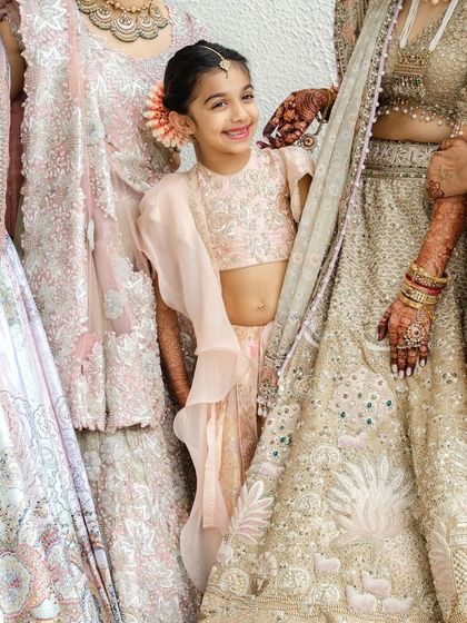 A close-up of the bride's lehenga and the flower girl, with a peek of the bride's rich henna stain.