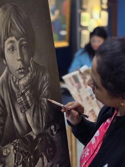 A student works on a charming and detailed portrait of a young boy with his toys, using a white glass marking pencil to capture a nostalgic feel.