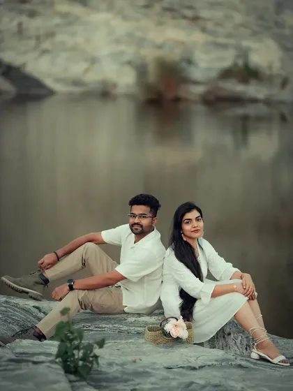 A serene portrait of a couple sitting back-to-back by a tranquil quarry lake. We use calm, natural settings to create a peaceful and reflective mood for your photos.