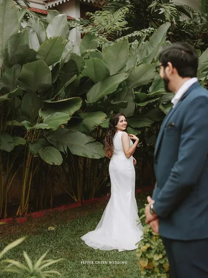 A "first look" style shot, with the groom waiting as his bride approaches, her glance full of anticipation and love.
