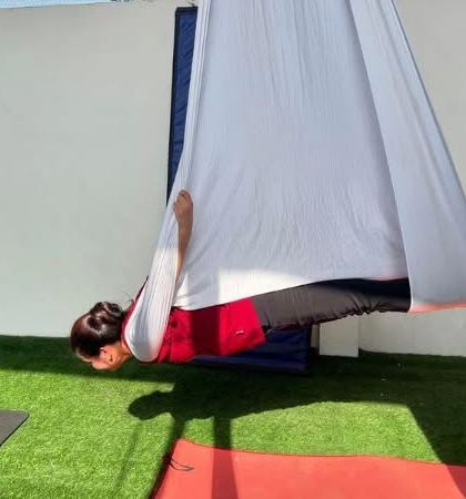 A student in a deep, relaxing inversion. The white hammock looks so peaceful against the green turf.