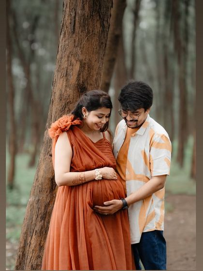 A loving embrace in the woods. This couple's maternity shoot is filled with warmth, featuring our comfortable and stylish rust-colored tulle gown.