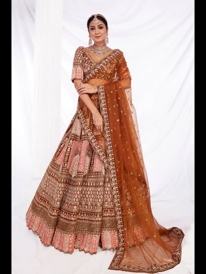 A full view of the stunning rust-colored bridal lehenga, showcasing its grand silhouette and detailed embroidery. A perfect statement piece for your wedding day.