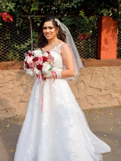 A full-length shot of the bride, looking happy and beautiful. The entire look is cohesive, from the dress to the hair and makeup.