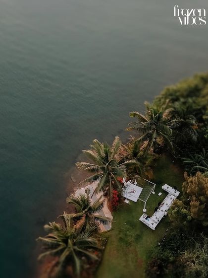A breathtaking top-down drone shot of an intimate white wedding ceremony by the sea. This perspective highlights the beauty and seclusion of the location.