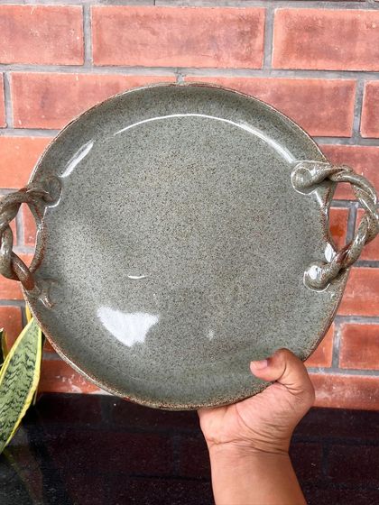 A large serving platter with unique braided handles, all made from clay. This piece shows the amazing details you can achieve with hand-building.
