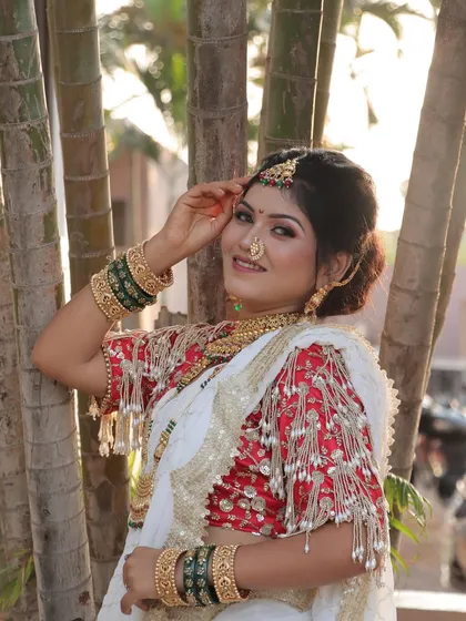 A happy and radiant bride posing amidst nature. Her complete look, from the makeup to the jewellery, is perfectly harmonized.