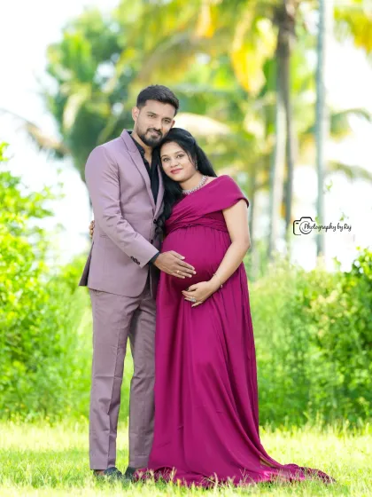 A classic couple's portrait in a beautiful garden. The mother-to-be's wine-colored gown and the partner's matching suit create a coordinated look.