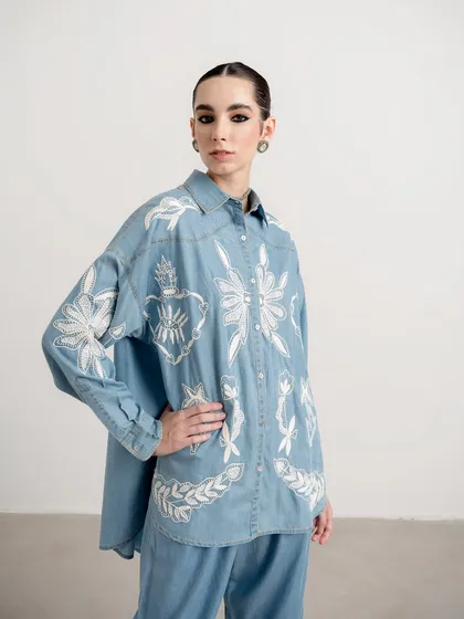 A look from the same Nakateki collection, this time a light-wash denim shirt with intricate white embroidery. The styling is simple to let the detailed craftsmanship of the piece stand out.