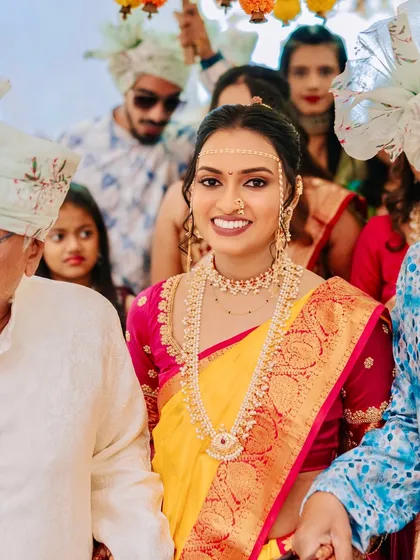 A beautiful Maharashtrian bride entering her wedding ceremony. Her two-tone yellow and pink saree is complemented by a soft, glowing makeup look.
