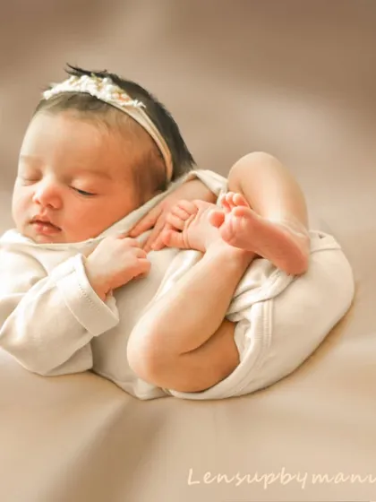 The natural, curled-up poses of a newborn are what make these sessions so special. This portrait captures that fleeting flexibility in a simple, elegant outfit, highlighting the baby's delicate form against a soft, neutral backdrop.
