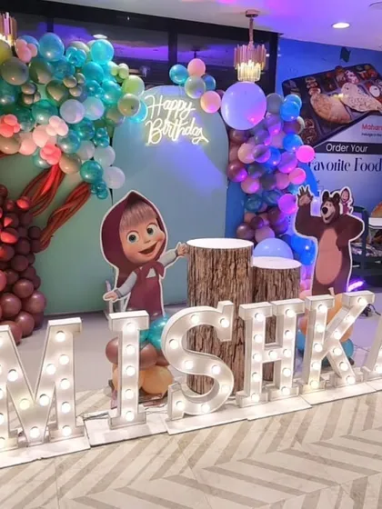 A detailed shot of the Masha and the Bear birthday decoration. You can see the marquee letters, character cutouts, and the custom balloon tree sculpture we created for the forest theme.