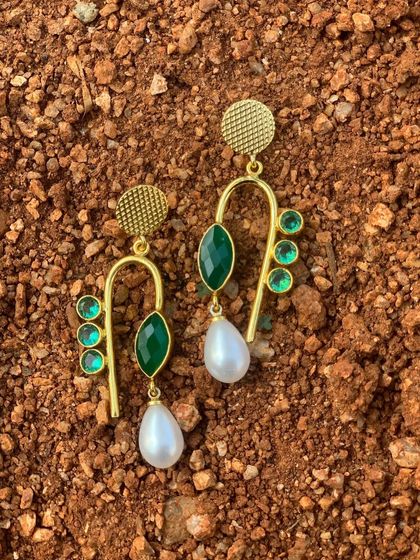 A full view of the green brass earrings against a natural backdrop. The combination of green stones, pearls, and gold-tone brass is simply stunning.